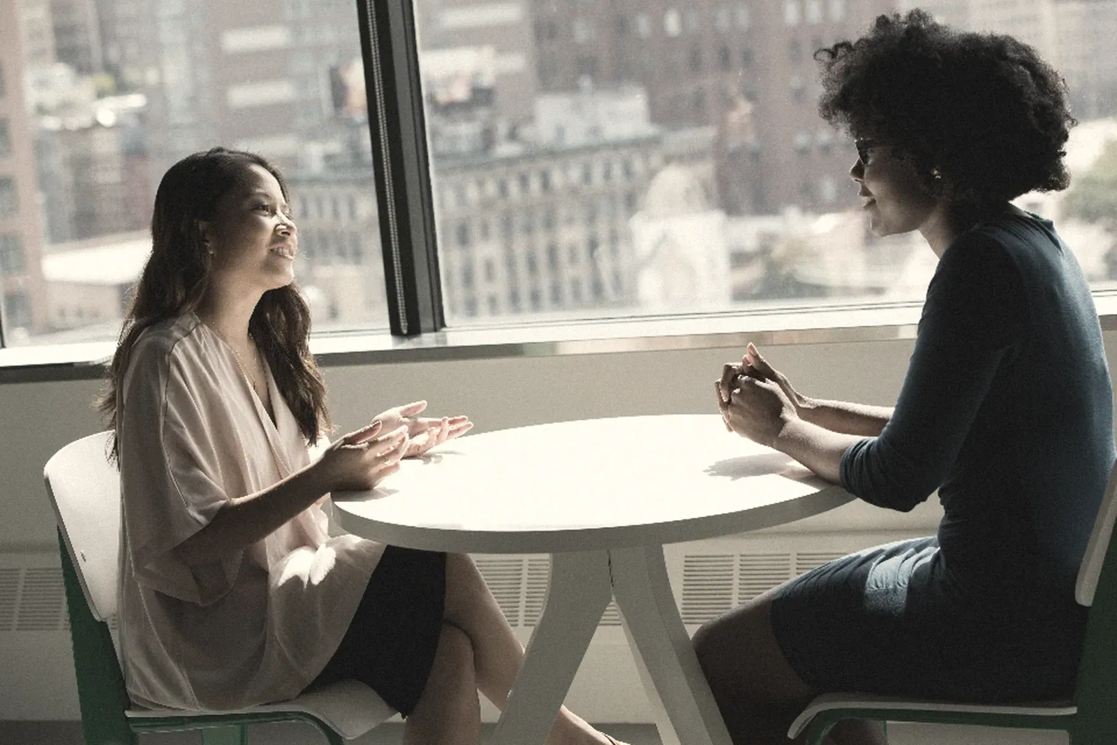 Two women meeting at a table by a window