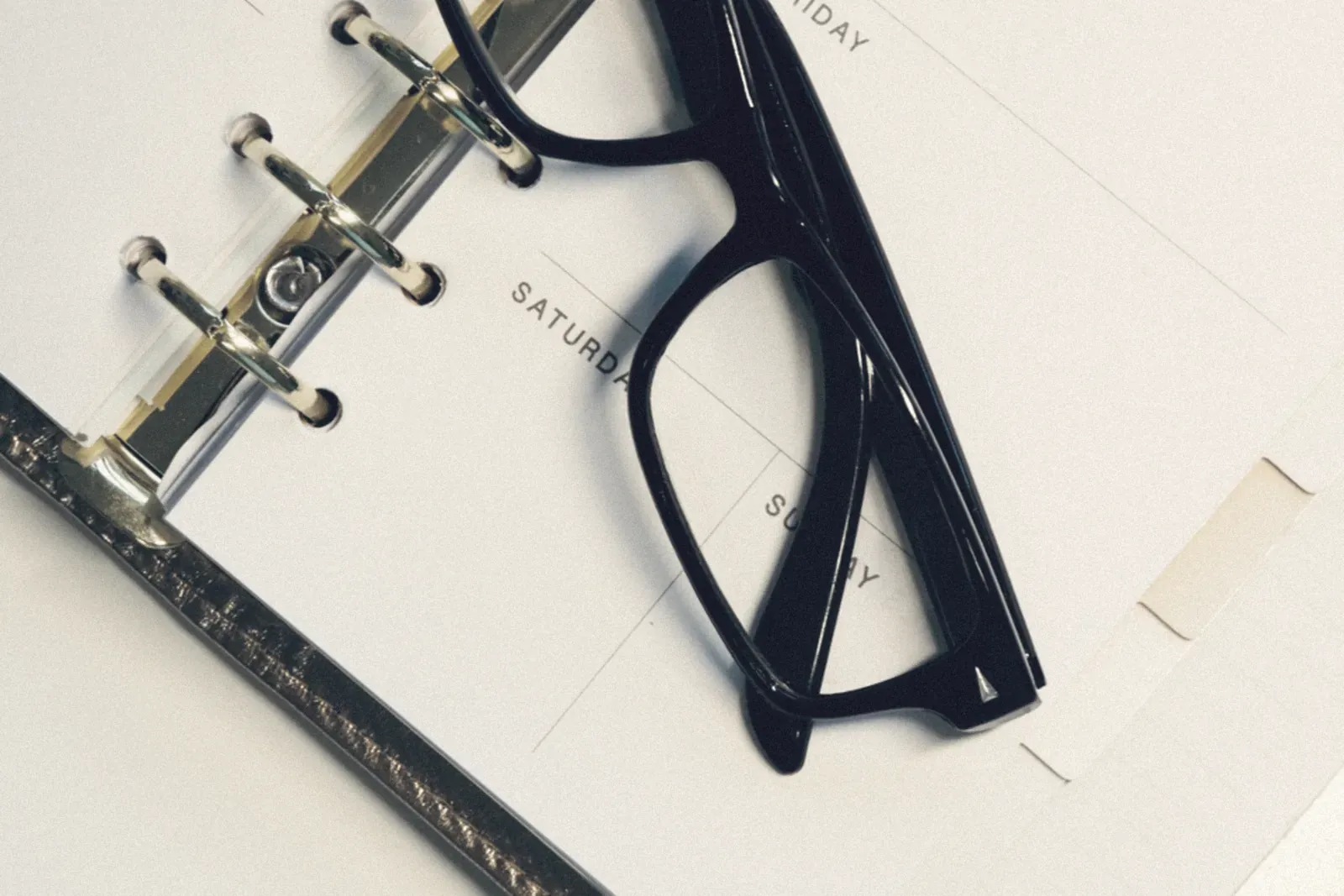 An open day planner with a pair of glasses