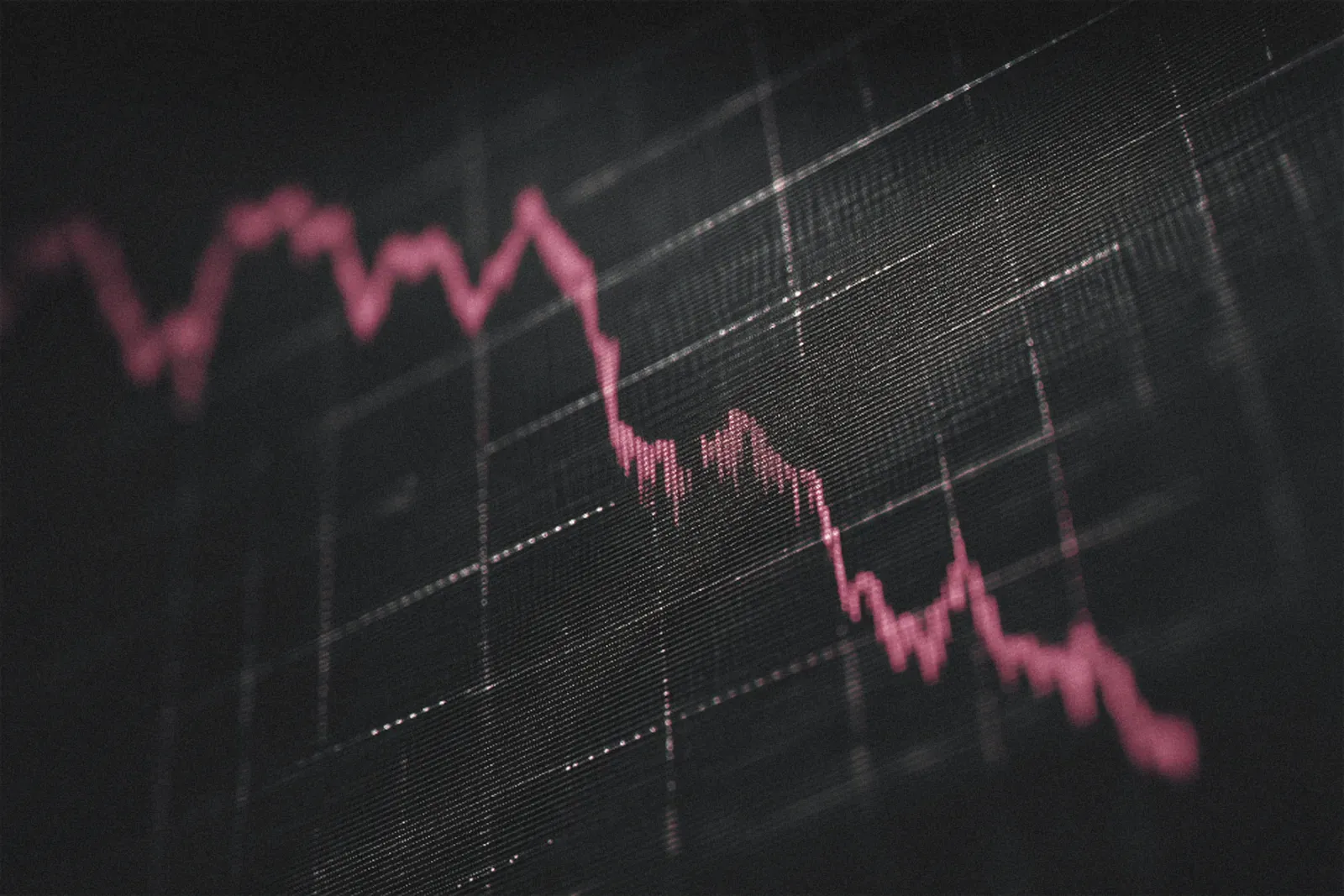 A stock price chart falling on a dark screen