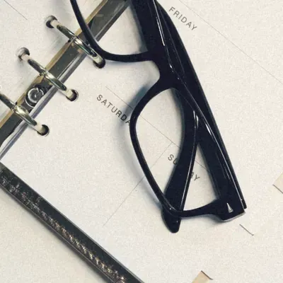 An open day planner with a pair of glasses